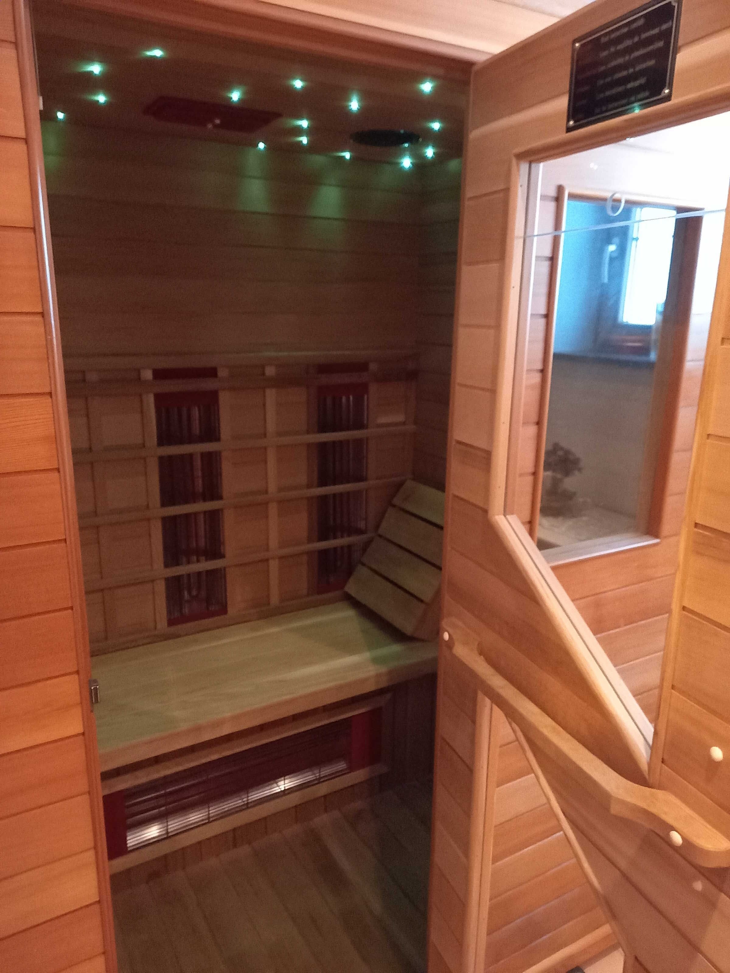 Eine Holzsauna mit Bänken, einem Fenster und einer Decke mit Lampen.