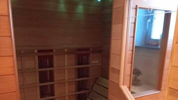 Eine Holzsauna mit Bänken, einem Fenster und einer Decke mit Lampen.