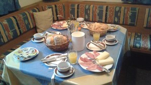 Mesa de café da manhã posta com pratos, pão, manteiga e suco.