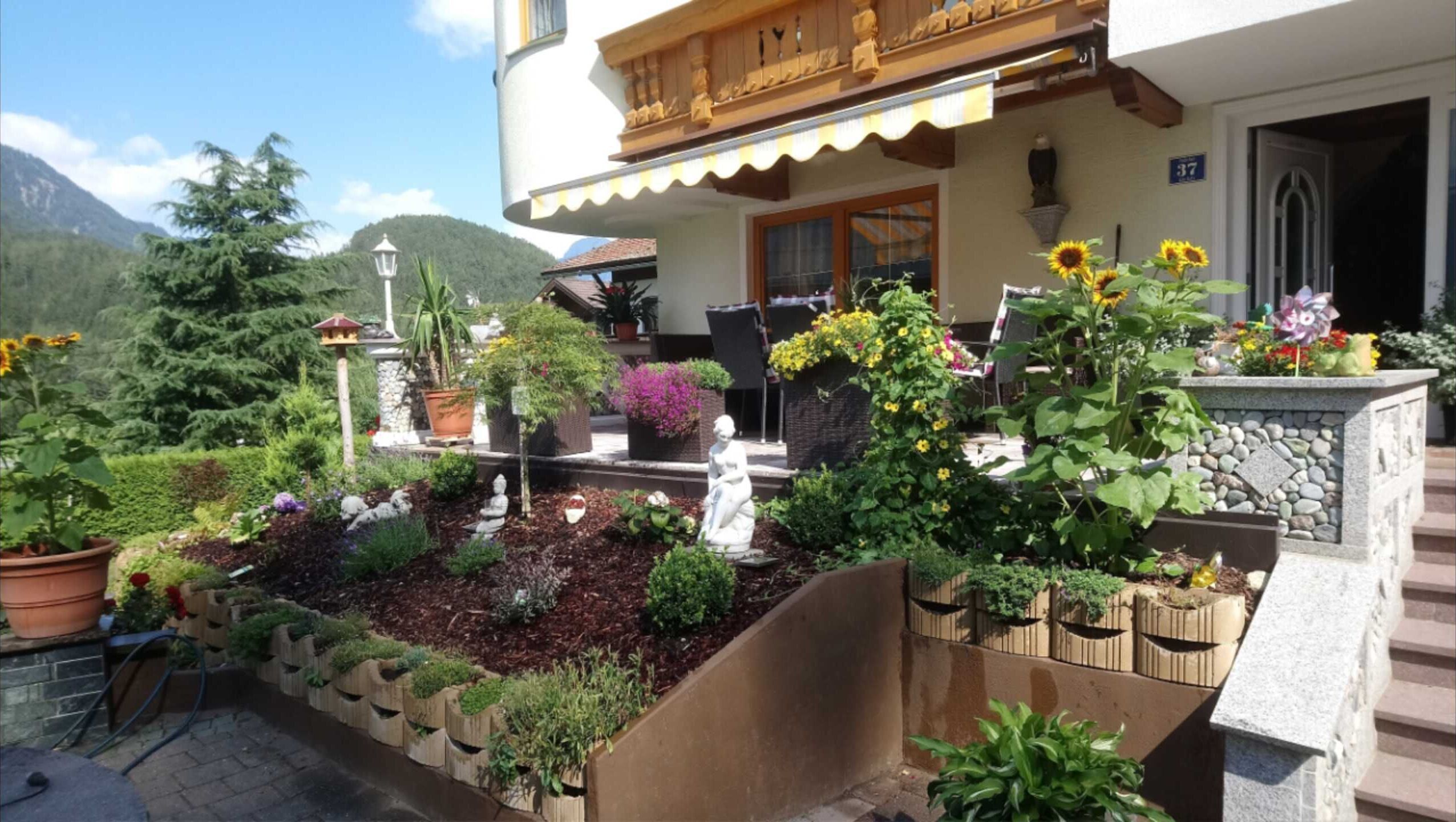 Ein Gebäude mit Garten, ein Balkon mit Holzgeländern und ein Berg im Hintergrund.