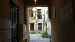 A narrow hallway with a view of a courtyard, featuring a building with multiple windows and a door. - StayPlus Central Apt Balcony (Oslo)