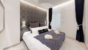 Ein modernes Schlafzimmer mit einem großen Bett, einem Kopfteil mit geometrischem Muster und einem Nachttisch mit Lampe.