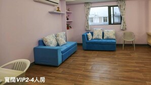 Una sala de estar con dos sofás azules, una silla blanca y piso de madera.