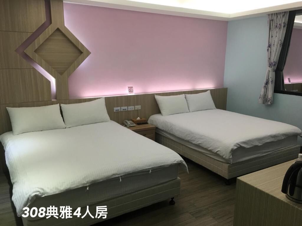 A 4-bedroom hotel room with two beds, a nightstand, and a desk.