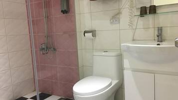 A bathroom with a toilet, a shower, a sink, and a checkered floor.