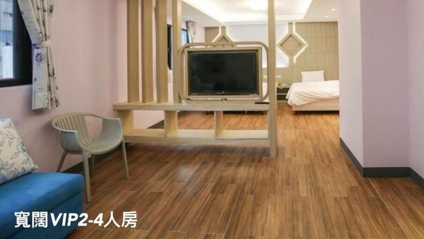 Una habitación de hotel moderna con un televisor fijado en una estructura de madera, una cama, un sofá azul y una silla.