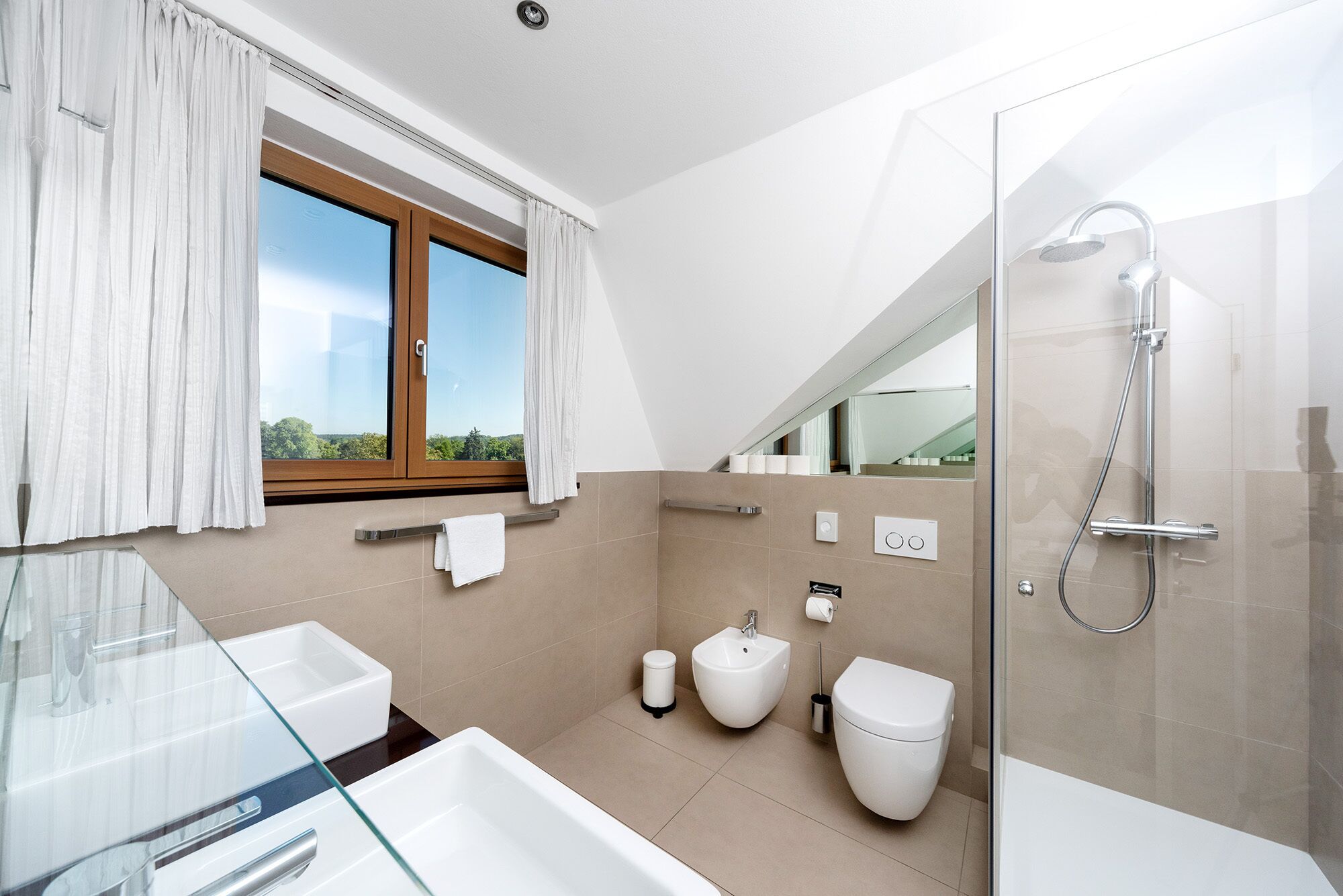A modern bathroom with a glass shower enclosure, a bidet, a toilet, and a glass sink.