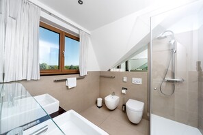 Une salle de bain moderne avec une douche à parois de verre, un bidet, des toilettes et un lavabo en verre.