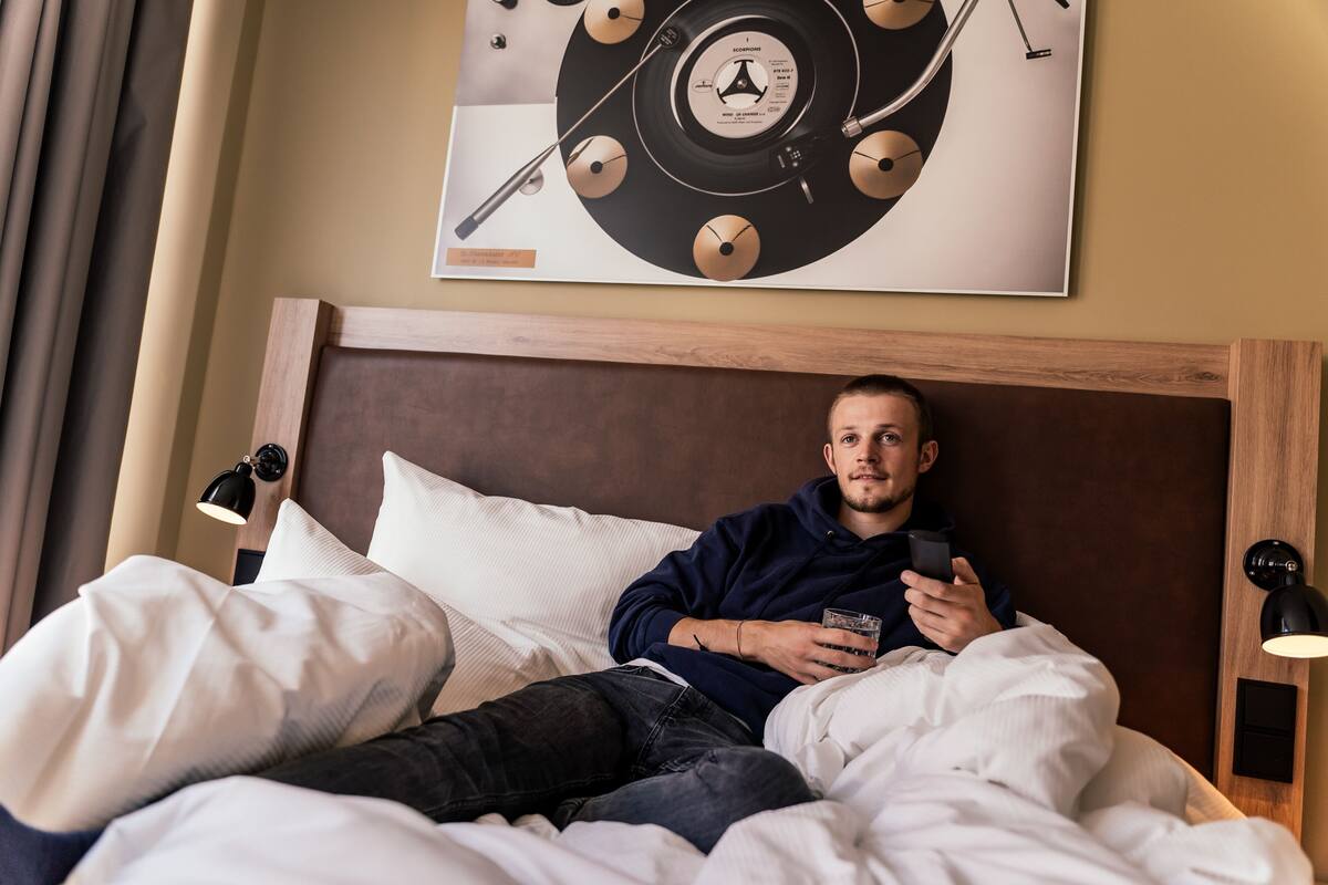 A man lying in bed with a poster of a vinyl record on the wall.