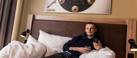 A man lying in bed with a poster of a vinyl record on the wall.