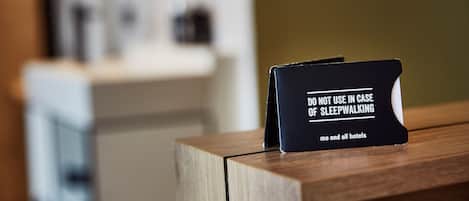 A black sign on a wooden surface with the text "DO NOT USE IN CASE OF SLEEPWALKING me and all hotels".