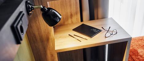 Un escritorio de madera con una computadora portátil, gafas y bolígrafos.