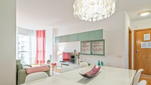 Eine moderne Küche mit Essbereich, mit einem weißen Tisch, grünen Schränken und einem Kronleuchter.
