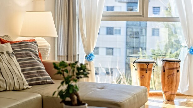 A living room with a sofa, cushions, a plant, and two wooden drums. - Apartamento&piscina cerca de Barcelona (Ripollet)