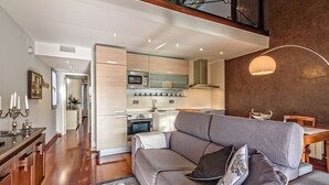 A modern living room with a grey sofa, a wooden coffee table, and a dining area with a table and chairs. - Apartamento con encanto en Barcelona&Playa (Badalona)