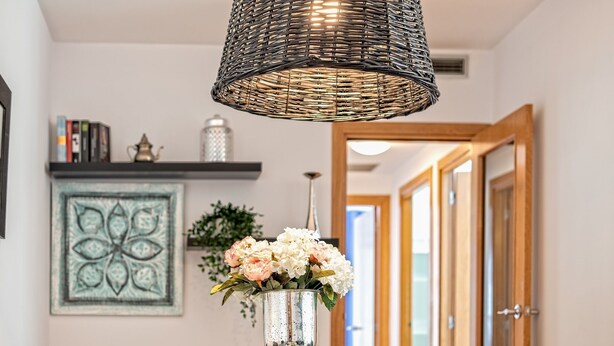 Ein Essbereich mit Tisch, Stühlen, einer Blumenvase, einer Pendelleuchte und einem Wanddekor.