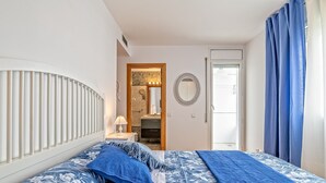 Ein Schlafzimmer mit einem Bett, einem Nachttisch, einem Spiegel und einer Tür zu einem Badezimmer.