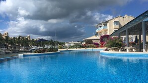 A swimming pool with a view of a building with balconies and a marina in the background.
