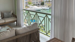A balcony with a view of a marina, a wicker sofa, and a table.