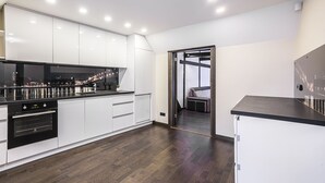 A modern kitchen with white cabinets, a black countertop, and a view of a cityscape at night. - WINWINSTAY Apartments Heart of Old Town (Riga)