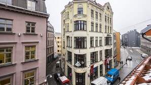 A corner building with a bakery sign, a cobblestone street, and a tram line. - WINWINSTAY Apartments Heart of Old Town (Riga)