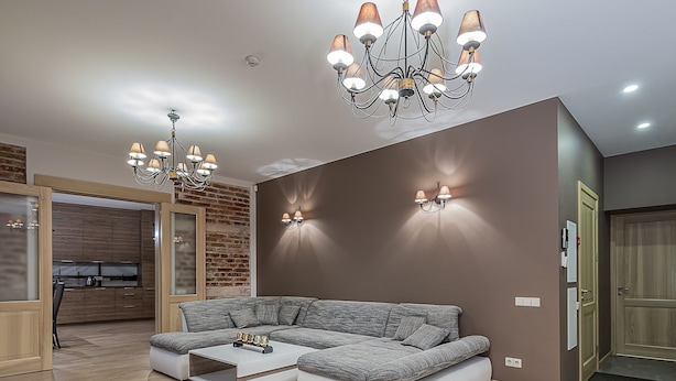 A modern living room with a sectional sofa, a coffee table, a chandelier, and a brick wall. - WINWINSTAY Apartments Heart of Old Town (Riga)