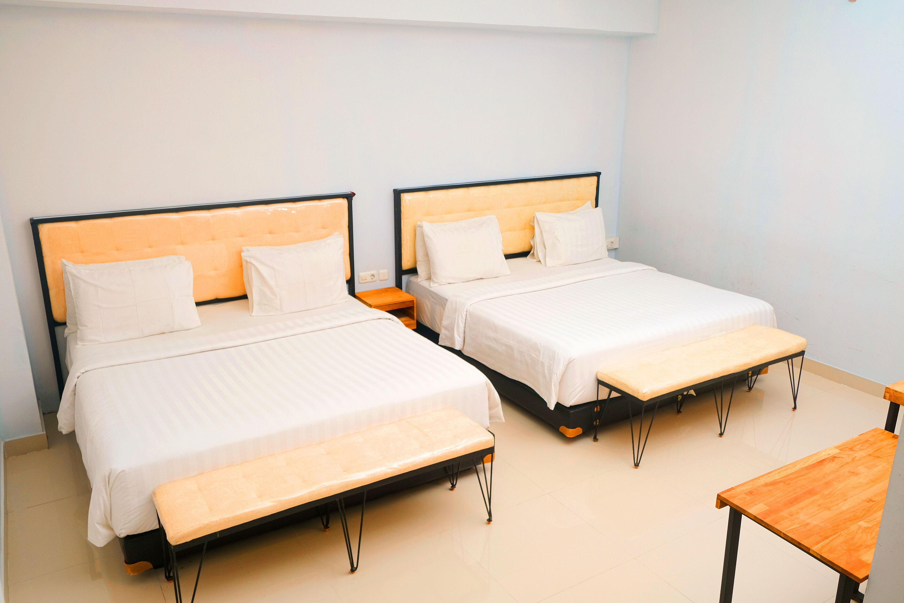 Une chambre d’hôtel avec deux lits, un banc et une petite table.