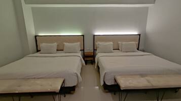 A twin room with two beds, each with a headboard, bedside tables, and a bench at the foot of the beds.