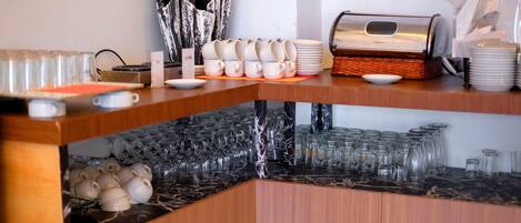 A bar area with stacked glasses, a coffee machine, and a plant.