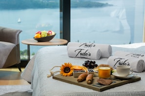 Uma bandeja de café da manhã bem organizada com frutas, doces e uma xícara de café sobre uma cama com toalhas com a etiqueta "Frida's Villa".
