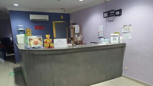 A reception desk with a grey counter, a water dispenser, a small statue, and various informational posters on the wall. - Healthy Home, Changkat Bukit Bintang (Kuala Lumpur)