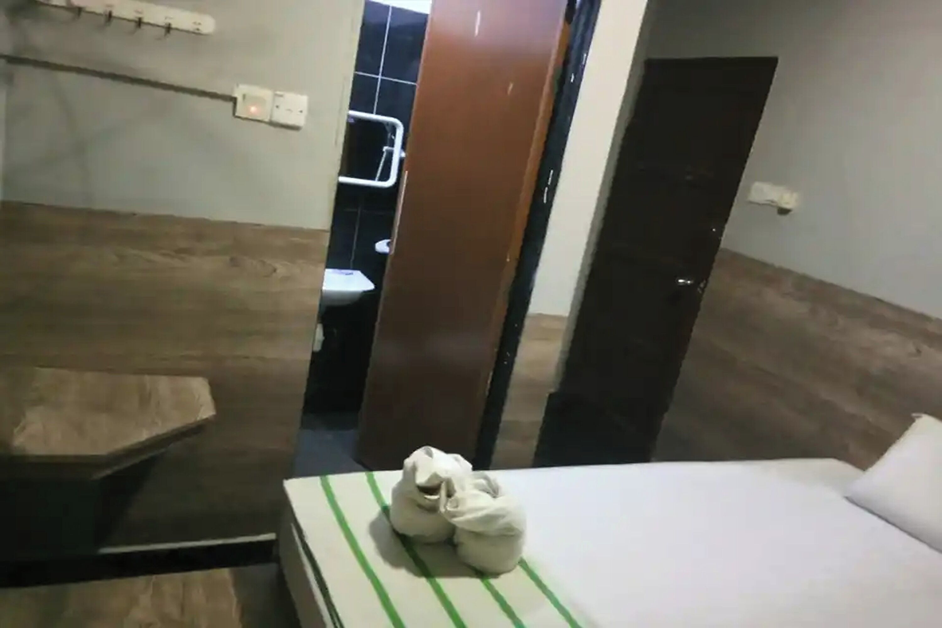Une chambre d’hôtel avec un lit, un petit coin salon et une salle de bain visible à travers une porte ouverte.