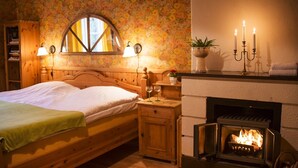 Une chambre confortable avec un lit en bois, une cheminée et un papier peint à motifs floraux.