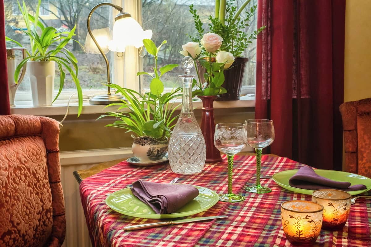 Una mesa de comedor dispuesta con platos verdes, una jarra de vidrio transparente y un candelabro.