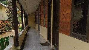 A covered corridor with tiled flooring, wooden exterior walls, and large windows.