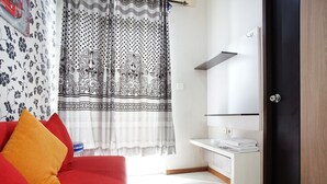 Et moderne hotelværelse med en rød sofa, en hvid vask og et stort spejl.