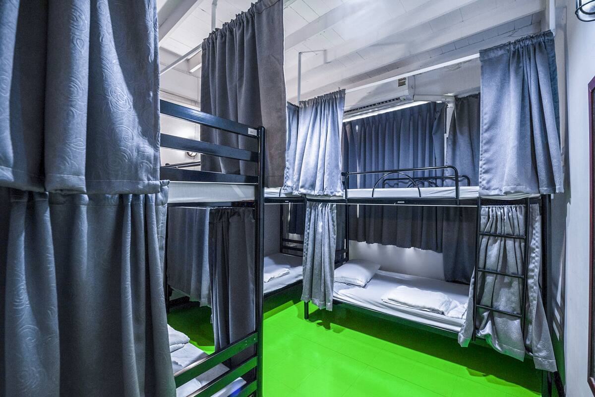 A bunk bed room with grey curtains, a green floor, and a window with curtains.