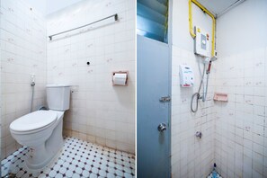 A bathroom with a toilet, a hand dryer, and a shower area with a control panel.