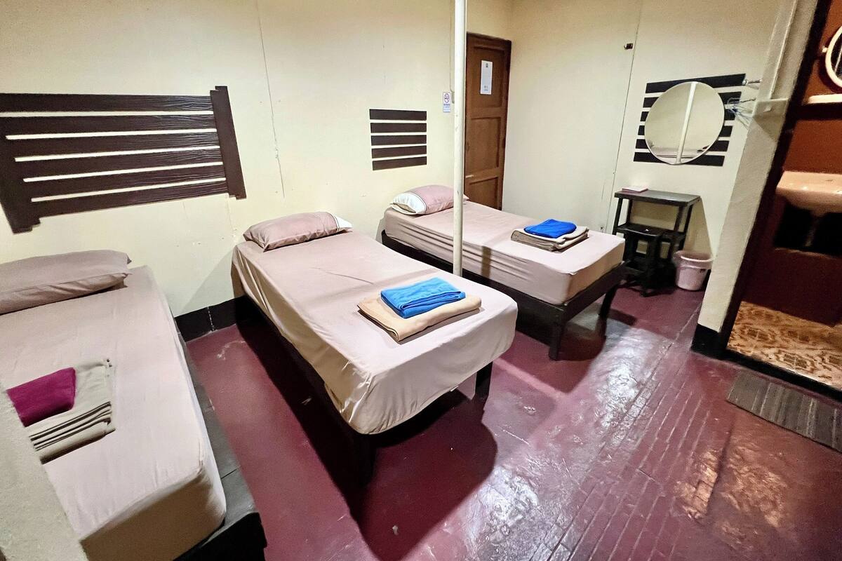A dormitory room with two single beds, a small table, a mirror, and a door.
