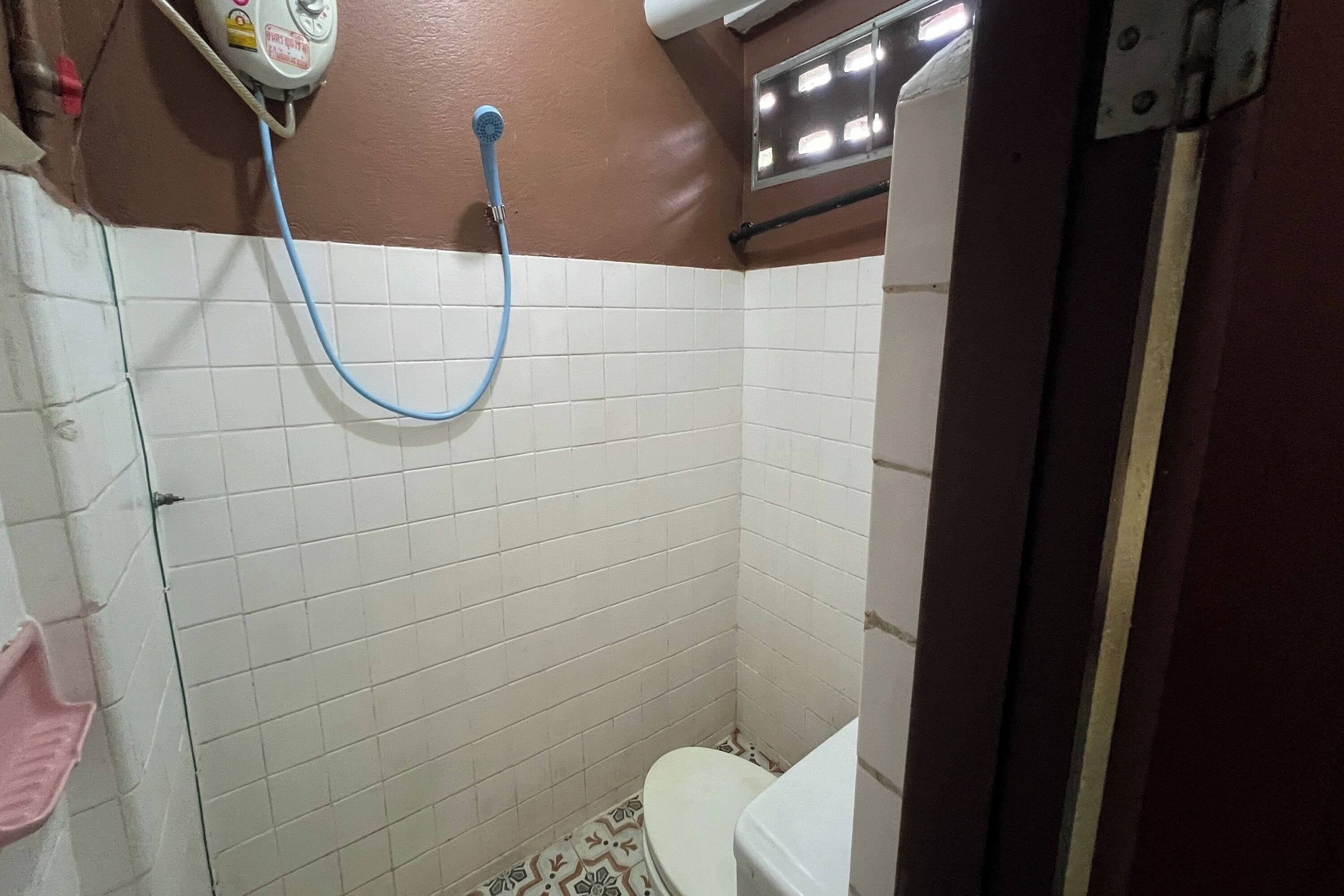 A small, tiled bathroom with a toilet, a shower, and a hand dryer.