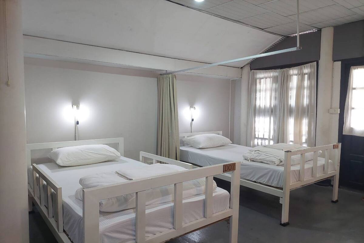 A room with two single beds, each with a white headboard and a bedside table.