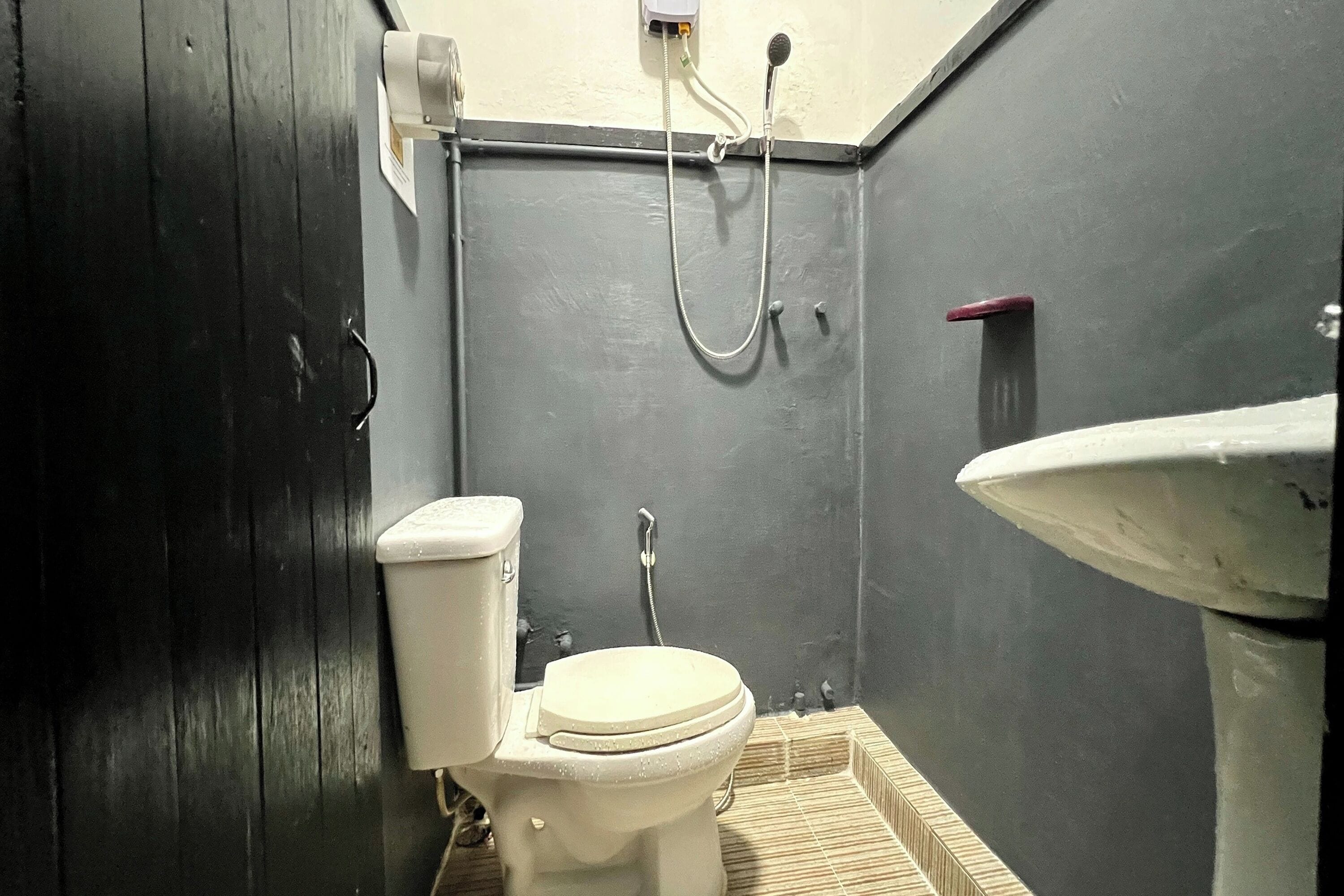 A small, narrow bathroom with a toilet, a shower, and a sink.