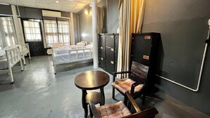 A hotel room with a bed, a small table, two chairs, a wardrobe, and a window with curtains. - Baan Lanna At Phrasingh (Chiang Mai)