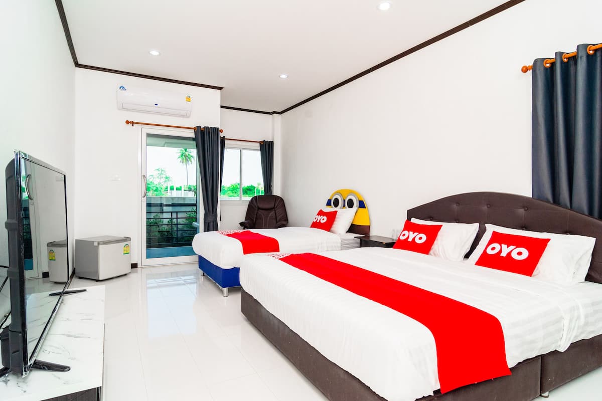 A hotel room with a large bed, a television, and a window with curtains.