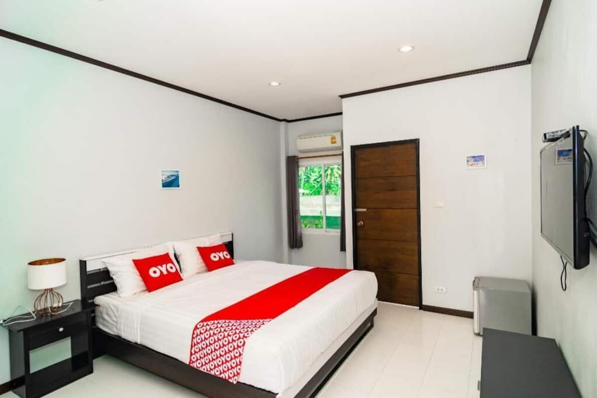 A hotel room with a bed, a nightstand, a TV, and a door.