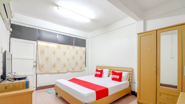 A bedroom with a bed, a wardrobe, a desk, and a window with curtains. - OYO 525 MRT Phetkasem 48 Place (Bangkok)
