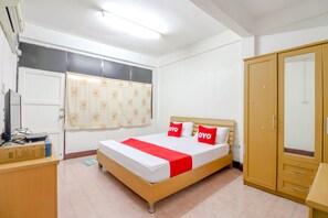 Een slaapkamer met een bed, een kledingkast, een bureau en een raam met gordijnen.