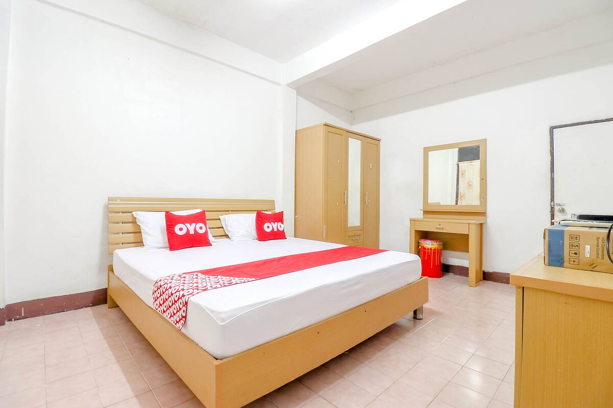 Ein Hotelzimmer mit Bett, Schrank, Nachttisch und Spiegel.
