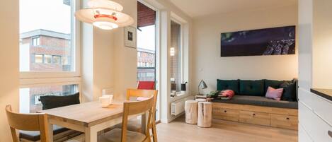 A modern living space with a dining area, a sofa, and a large window.