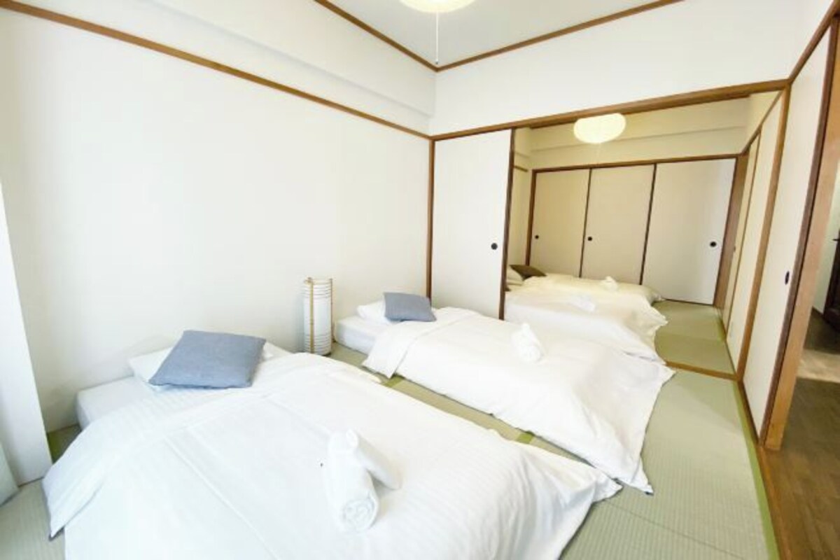 A hotel room with two beds, a small seating area, and a mirror reflecting the room.